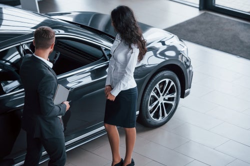 Two people at a car dealership