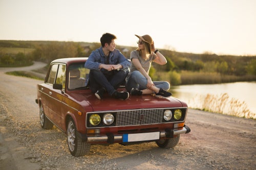 Two people sitting on the hood of a car