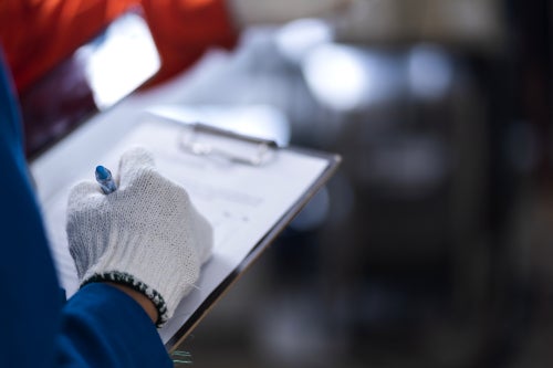 Person writing on a clipboard