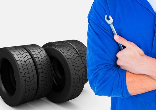 Person holding wrench in front of tires