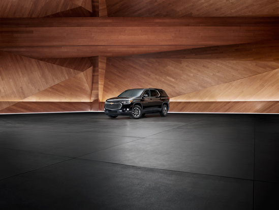 A sleek black SUV is parked in a modern showroom with geometric wooden walls and a polished floor. The setting exudes a sophisticated and elegant tone.