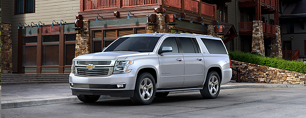 A silver SUV is parked in front of a modern building with stone and wood accents. The setting conveys a sense of luxury and rugged elegance.