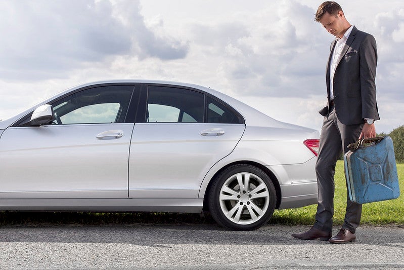 Guy holding gas can near a car