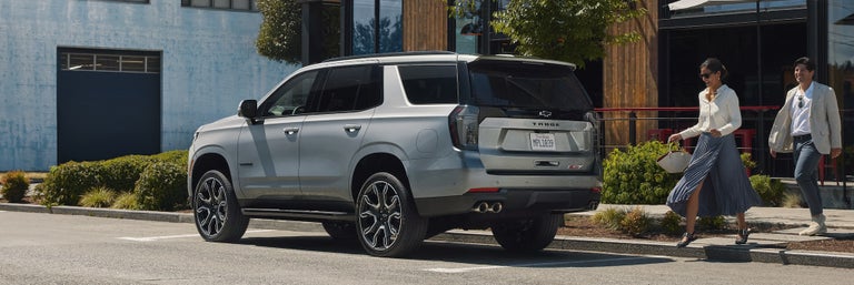 A couple approaching a 2025 Chevrolet Tahoe SUV Parked on the street outside a business
