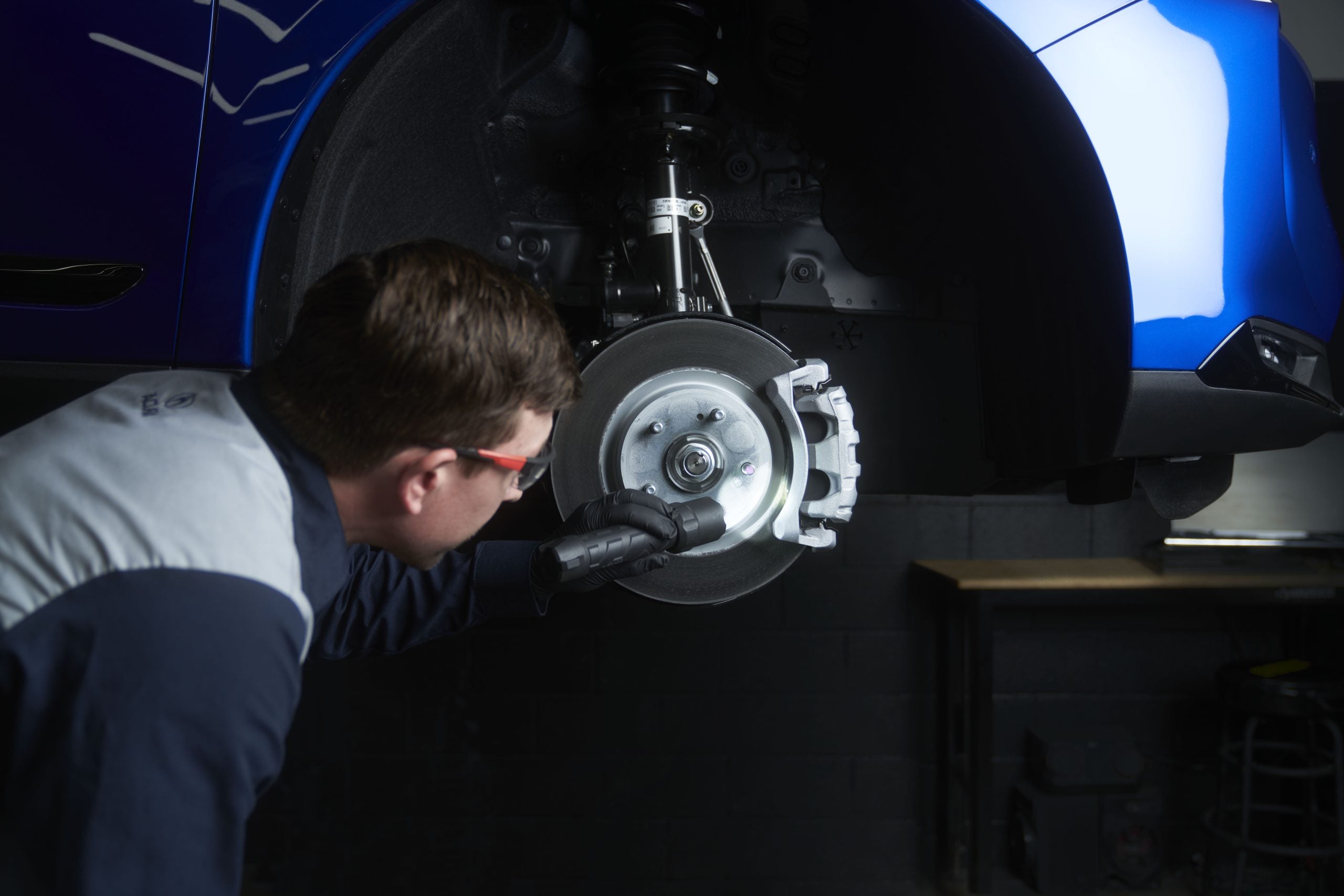 A mechanic inspecting the brake system of a car in a workshop.