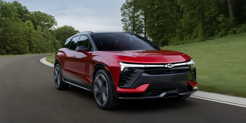 A red 2026 Chevy Blazer EV driving down an open road.