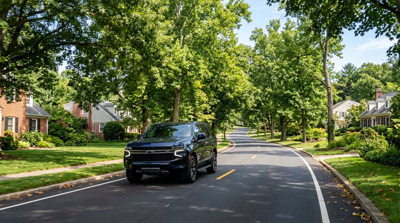 Dark blue Chevrolet SUV driving down a tree-lined suburban street. (Representative image for illustration purposes only. Actual vehicle may vary based on trim and configuration.)