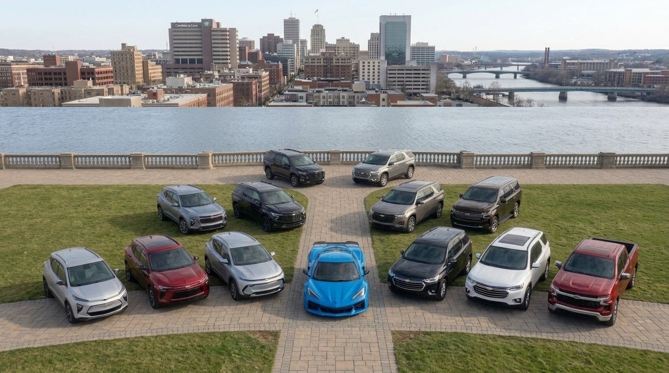 A fleet of Chevrolet SUVs, trucks, and a bright blue Corvette arranged in a semi-circle facing a city skyline. (Representative image for illustration purposes only. Actual vehicle may vary based on trim and configuration.)
