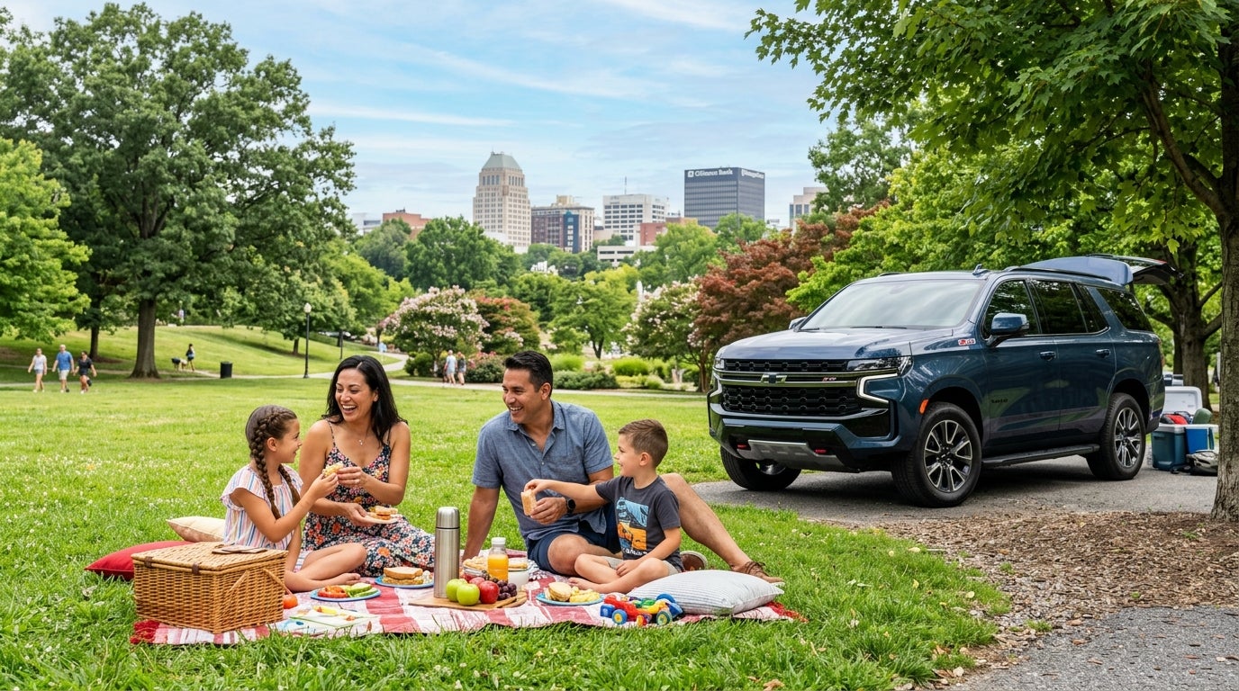 A family enjoys a picnic on a park lawn next to a blue Chevrolet SUV, with a city skyline in the background. (Representative image for illustration purposes only. Actual vehicle may vary based on trim and configuration.)