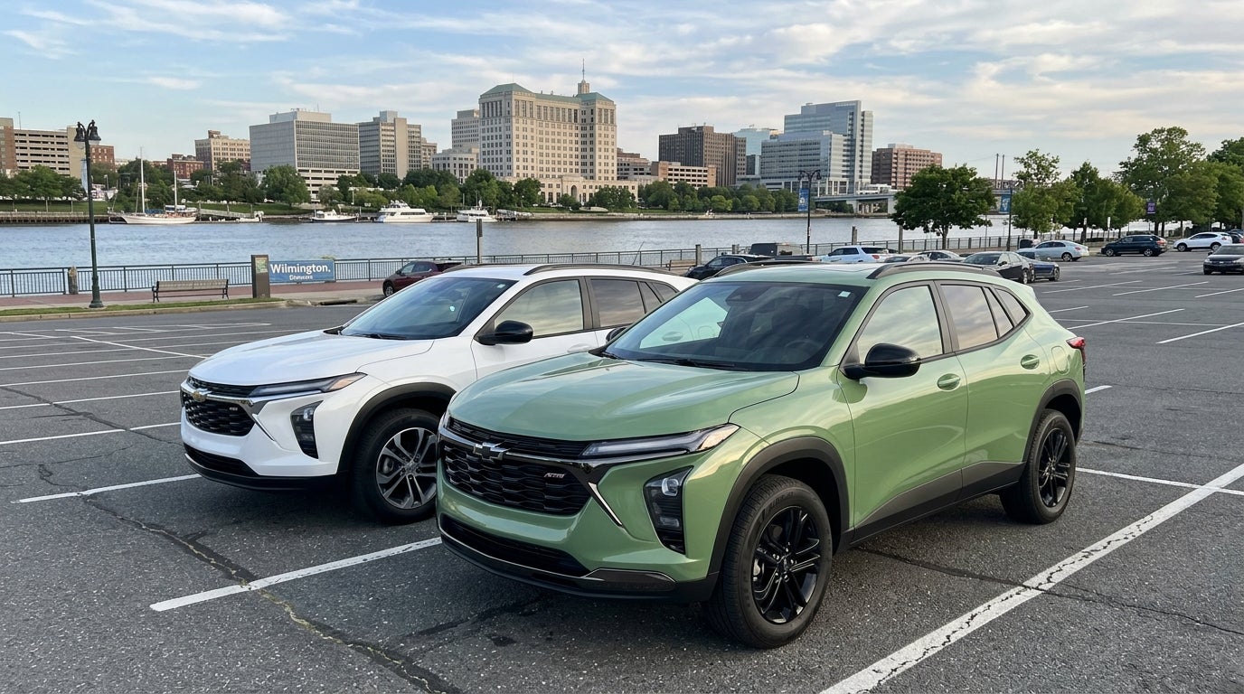 Two Chevrolet Trax compact SUVs, one green and one white, parked in a lot with the Wilmington skyline in the background. (Representative image for illustration purposes only. Actual vehicle may vary based on trim and configuration.)