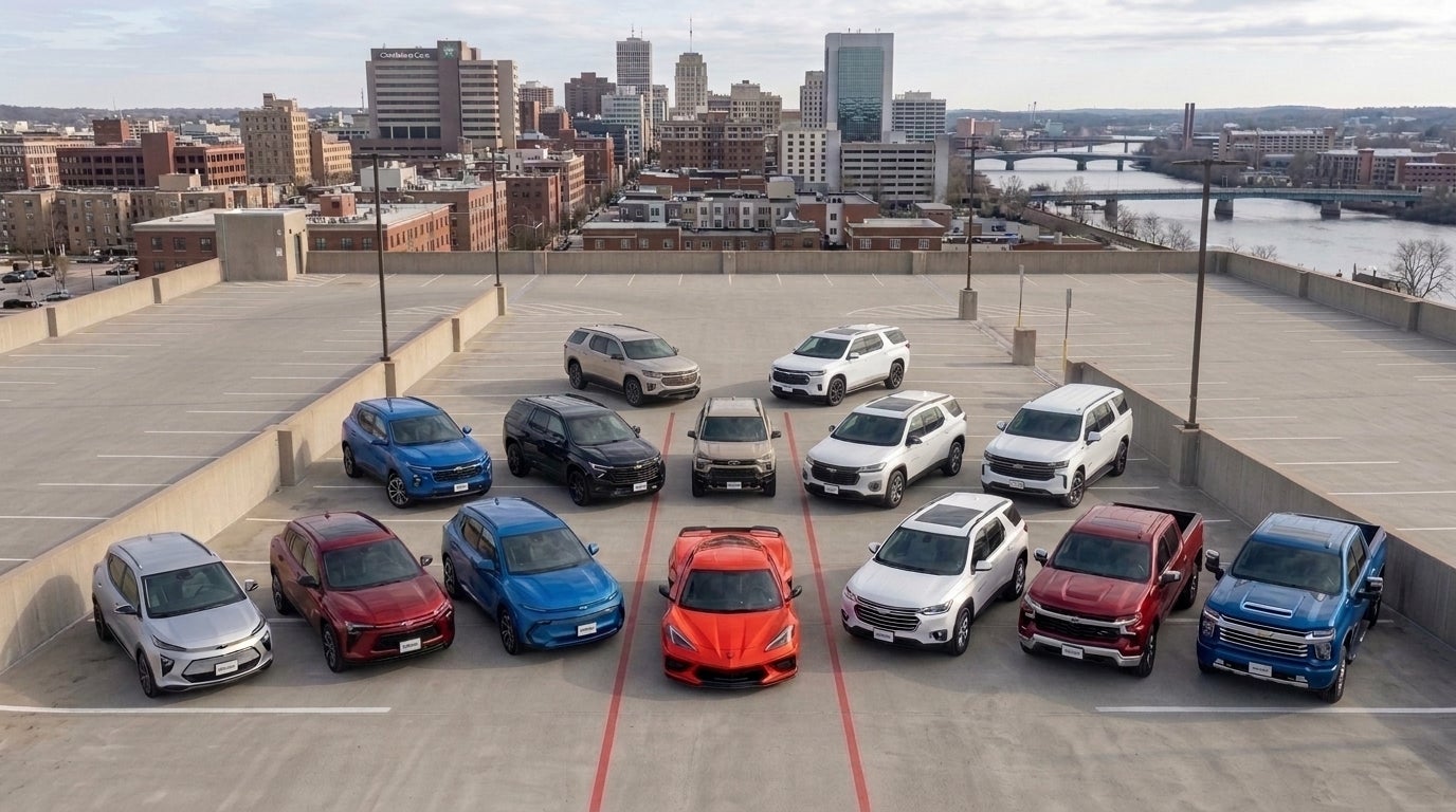 A lineup of Chevrolet SUVs, trucks, and a red Corvette parked on a rooftop deck overlooking a city skyline. (Representative image for illustration purposes only. Actual vehicle may vary based on trim and configuration.)