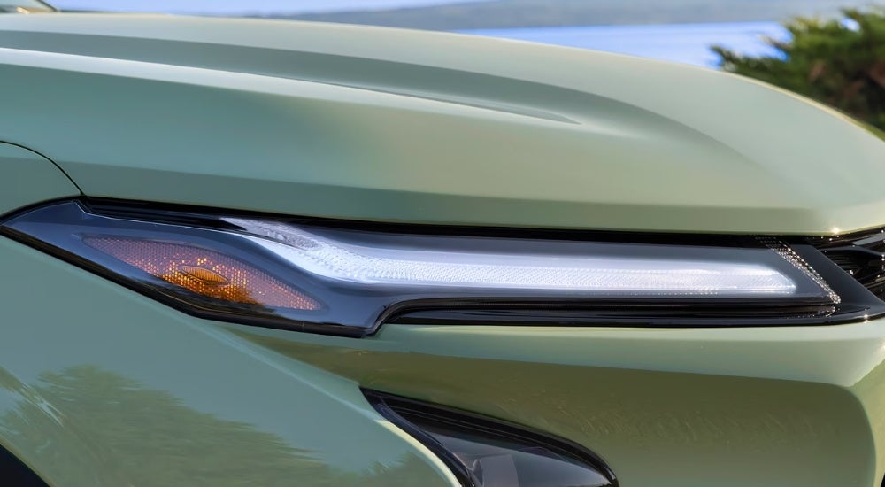 The passenger side headlight on a green 2024 Chevy Trax.
