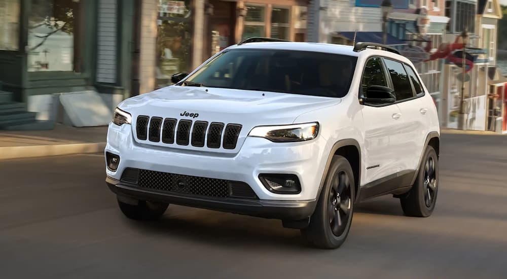 White 2023 Jeep Cherokee driving on a city street.