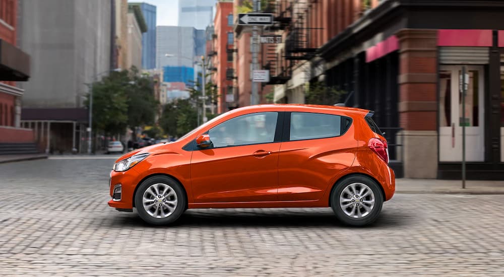 An orange 2022 Chevy Spark driving after looking at budget cars for sale.