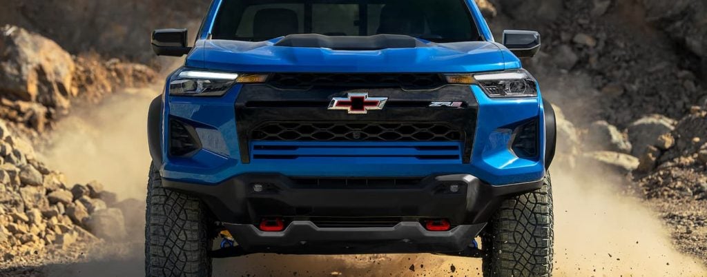 Blue Chevy Silverado driving on a dirt road.