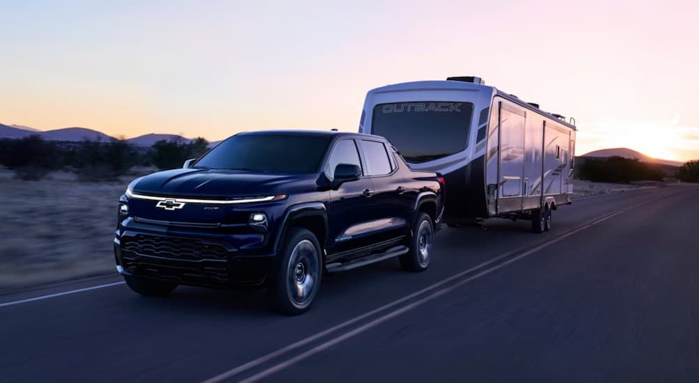A black 2024 Chevy Silverado EV RST towing a trailer.