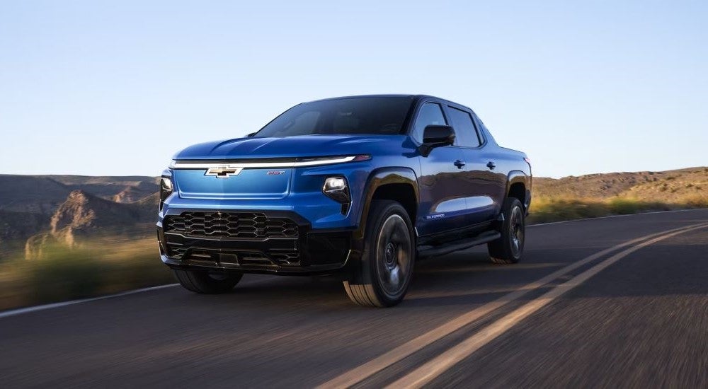 A blue 2024 Chevy Silverado EV RST driving down an open road.