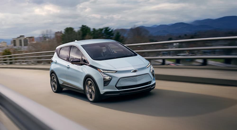 A blue 2022 Chevy Bolt EV driving on a bridge.