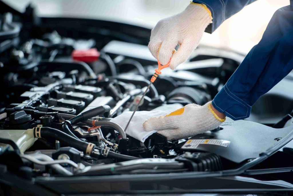 Mechanic testing oil level of an engine.