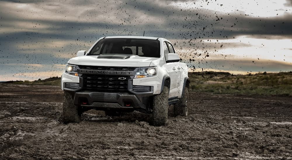White 2022 Chevy Colorado ZR2 off-roading on a muddy path.
