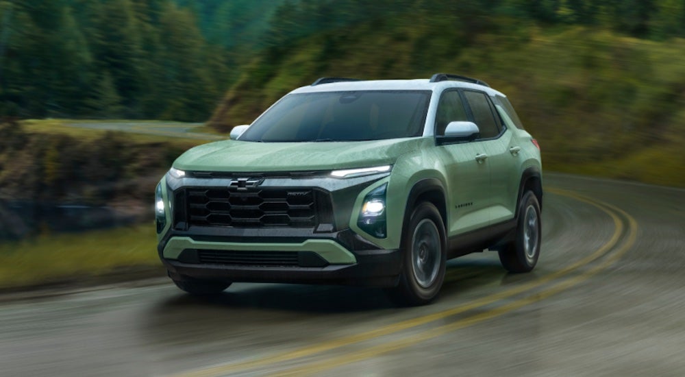 A green 2025 Chevy Equinox ACTIV driving around a bend.