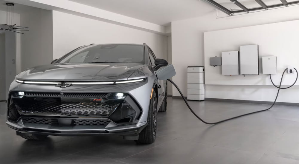 A grey 2025 Chevy Equinox EV plugged into a charger.