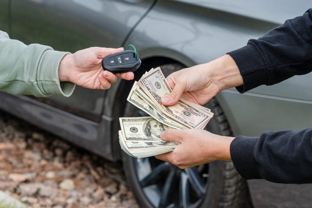 People exchanging money for a car key.