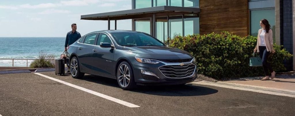 Black 2022 Chevy Malibu parked by a beach house.