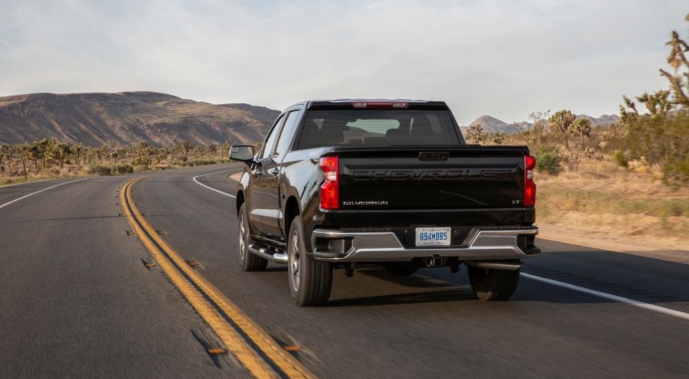A black 2022 Chevy Silverado 1500 LT driving to Castroville Chevy dealership.