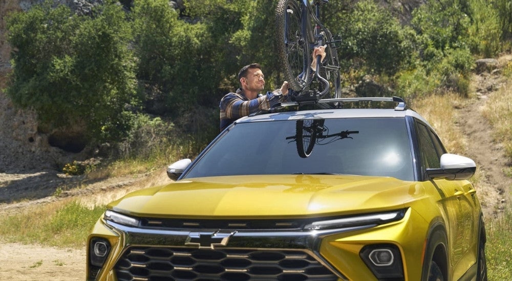 Person securing a bike to the roofrack of a 2024 Chevy Trailblazer ACTIV.