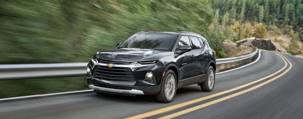 A black 2022 Chevy Blazer is shown from the front driving on an open road.