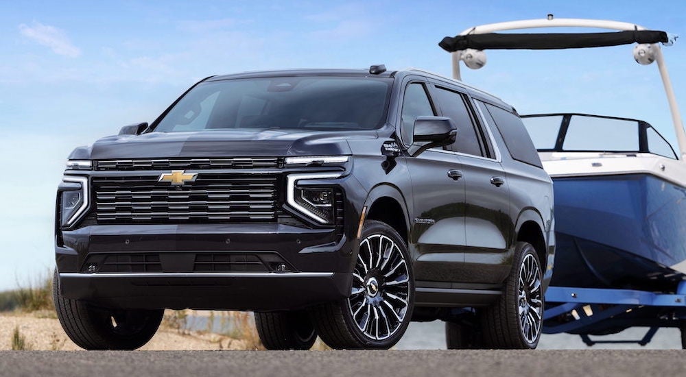 A black 2025 Chevy Suburban High Country towing a boat.