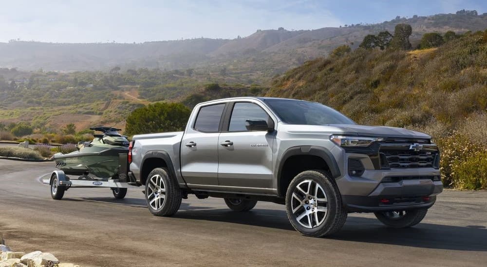 Grey 2026 Chevy Colorado towing a boat off-road.