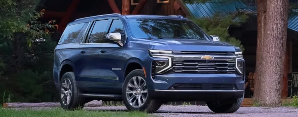 A blue 2025 Chevy Suburban High Country parked by a campsite.