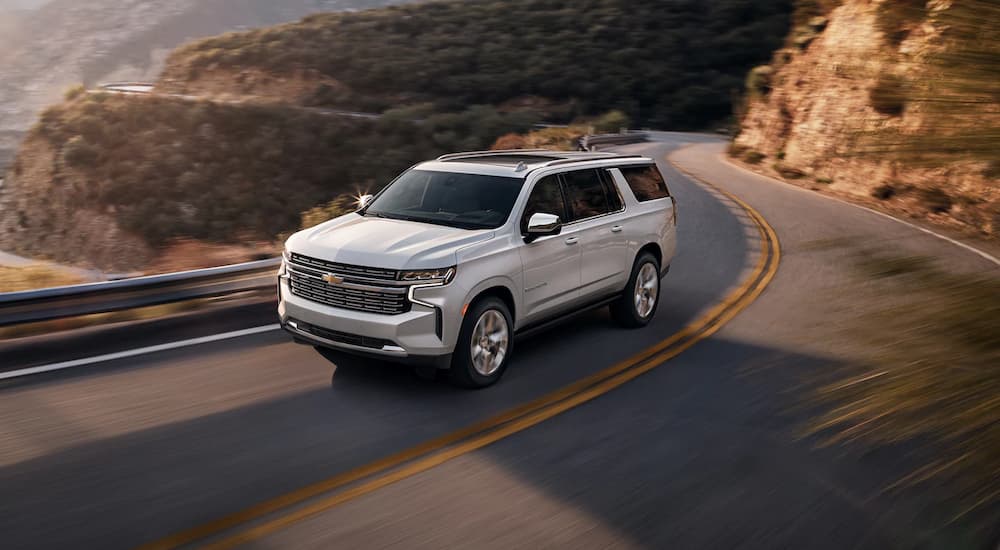 White 2022 Chevy Suburban LT driving on a winding road.