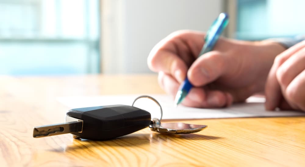 Set of keys on a table as a person fills out paperwork.