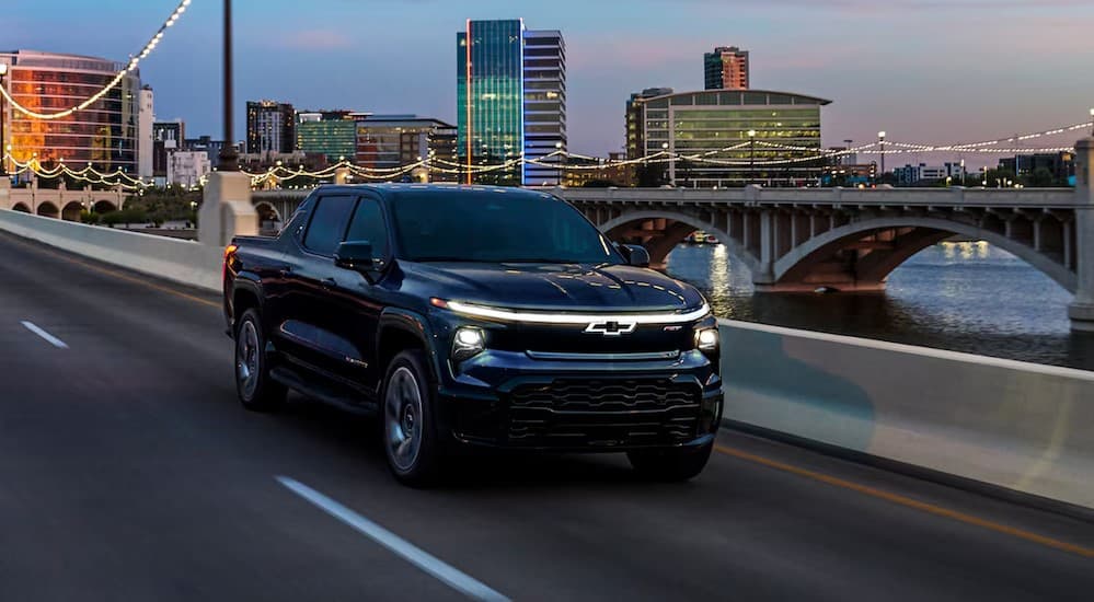 A black 2024 Chevy Silverado EV RST driving on a bridge.