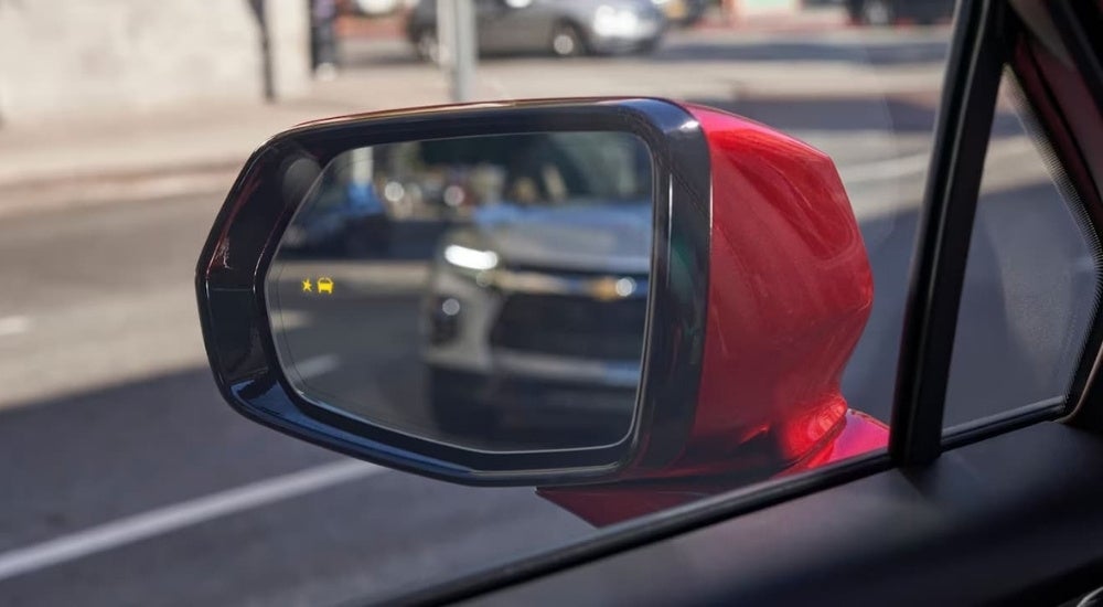 Blind spot monitoring icon on the mirror of a red 2023 Chevy Blazer.
