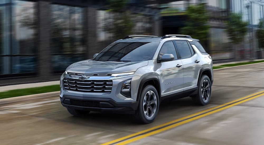 Silver 2026 Chevy Equinox driving down a city street.
