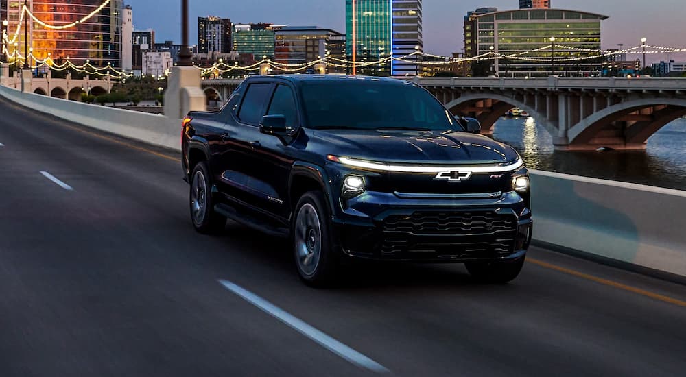 A black 2025 Chevy Silverado EV driving down a road.