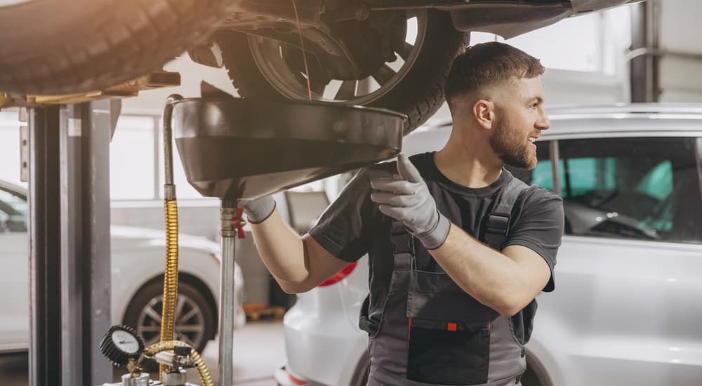 A mechanic draining oil out of a vehicle.