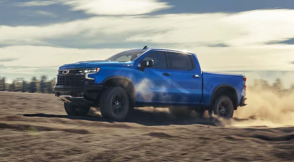 Blue 2026 Chevy Silverado 1500 off-roading in a sandy area
