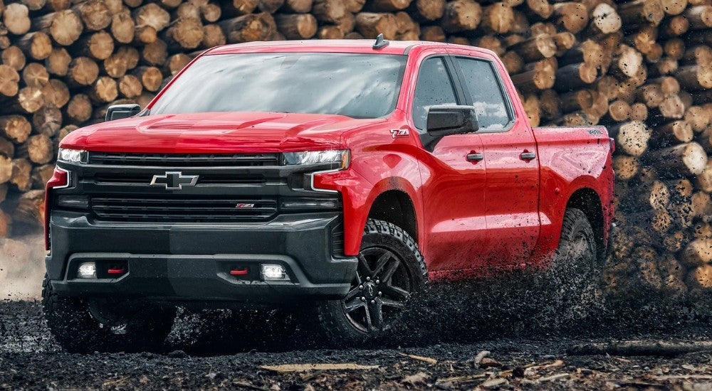 A red 2022 Chevy Silverado 1500 TrailBoss Z71 LTD is kicking up mud.