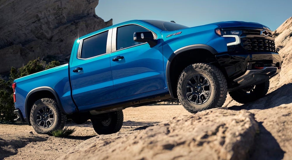 A blue 2024 Chevy Silverado 1500 ZR2 driving up a hill.