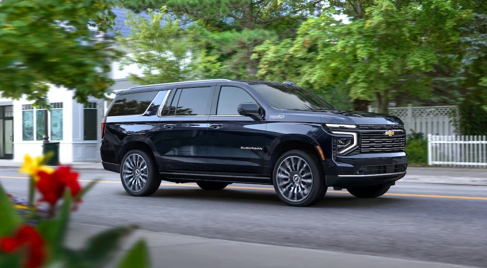 A black 2025 Chevy Suburban High Country driving through a city.
