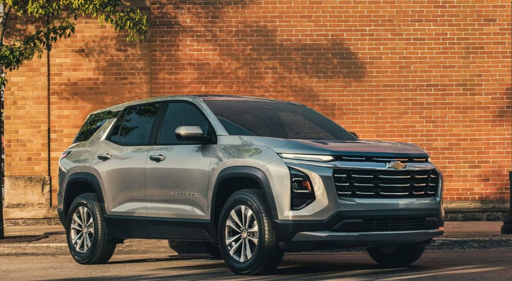 A silver 2026 Chevy Equinox parked in front of a brick wall.