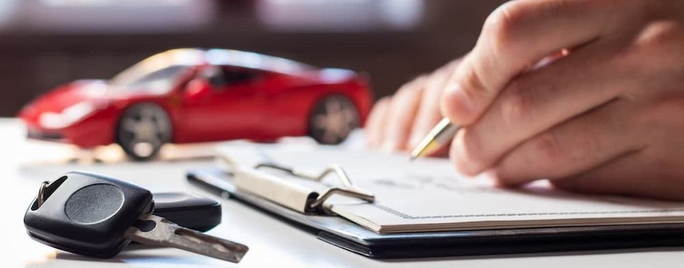 A person signing papers on a desk.