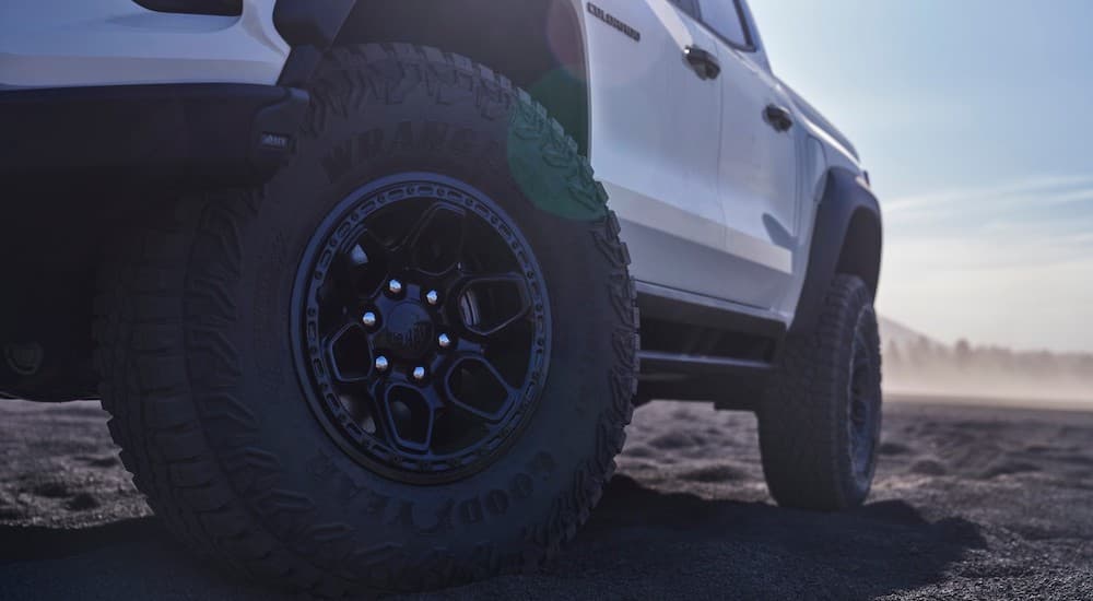 Close-up on the wheels of a white 2024 Chevy Colorado ZR2 Bison parked in a desert.