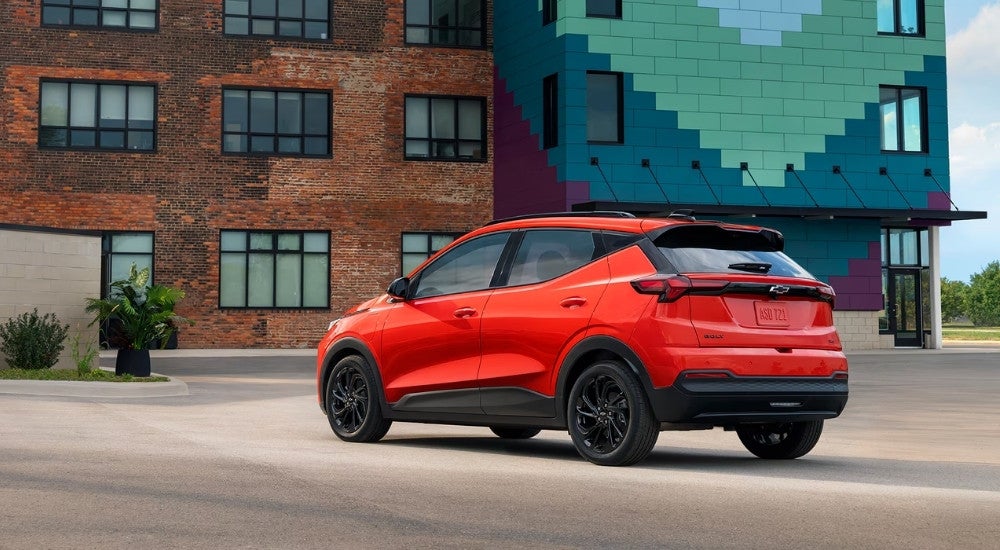 A red 2027 Chevy Bolt parked in a city