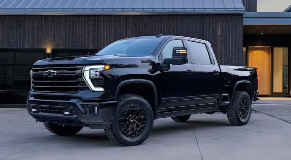 A black 2023 Chevy Silverado 2500 HD parked near a house.
